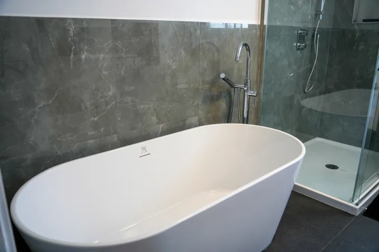 Bain autoportant blanc devant un mur de céramique gris marbré
