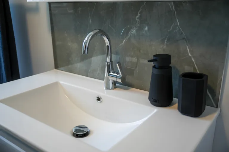 Robinet de lavabo chromé sur vasque blanche et dosseret de céramique