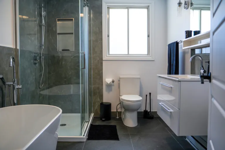 Salle de bain rénovée par ARJ Construction : douche en céramique grise, bain autoportant et robinetterie chromée